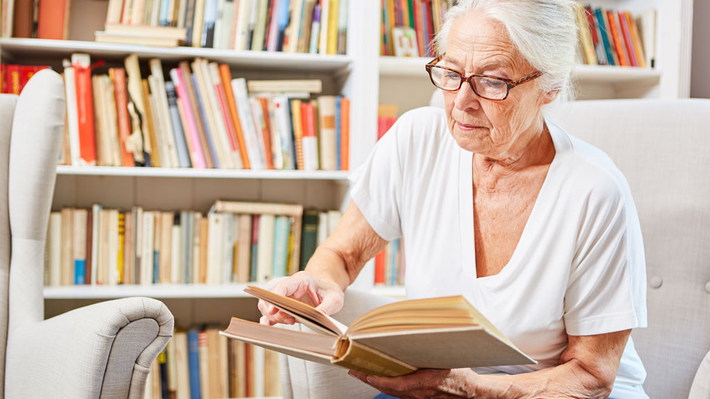 Personne consultant un livre ancien relié cuir dans un salon chaleureux